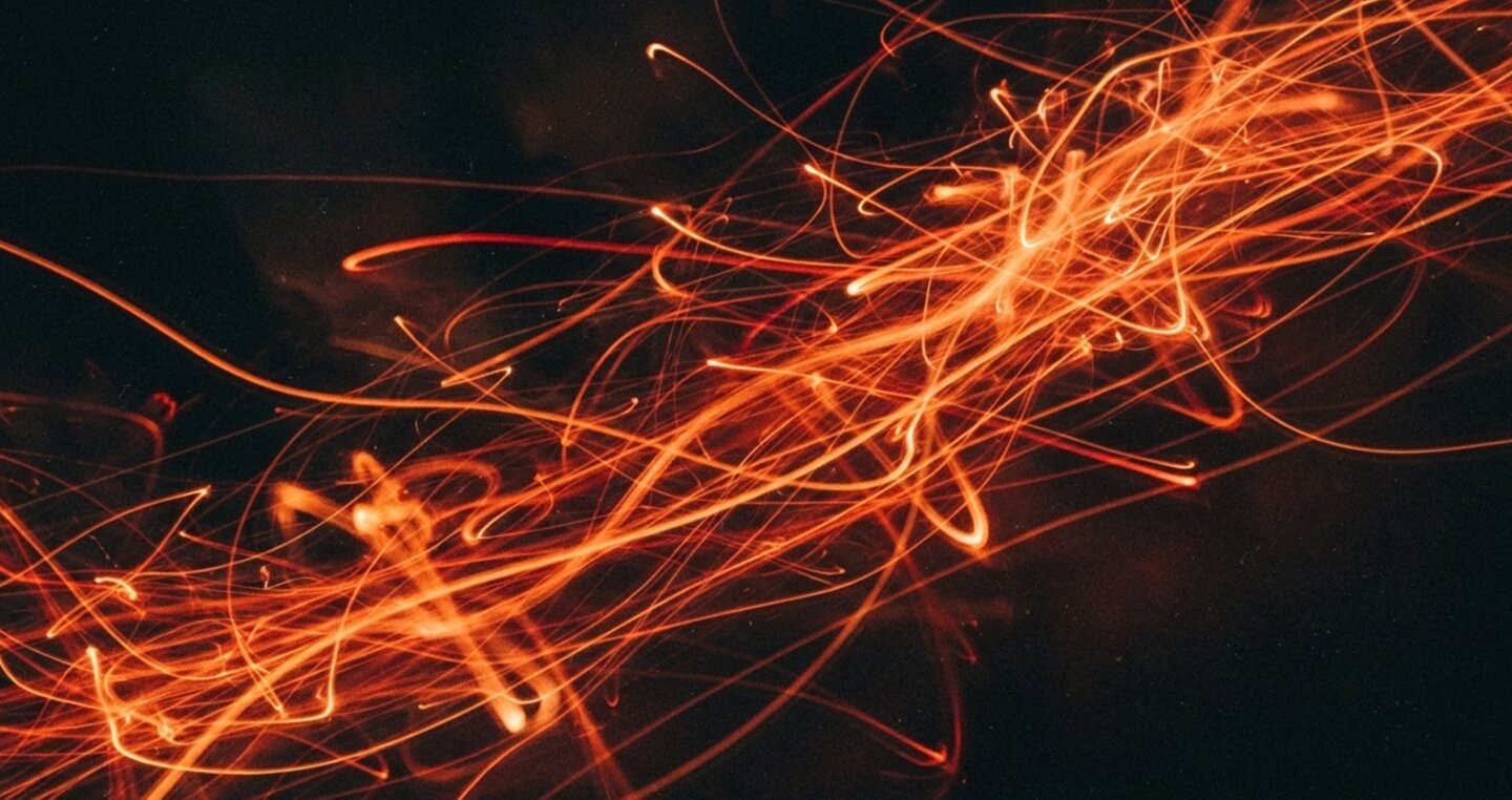 Long-exposure streaks of orange light tangled across a dark background
